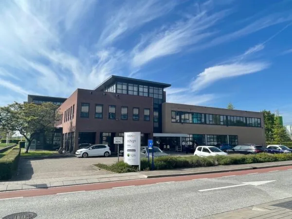 Kantoorgebouw aan de Rivium 4e Straat met geparkeerde auto's en een helderblauwe lucht.